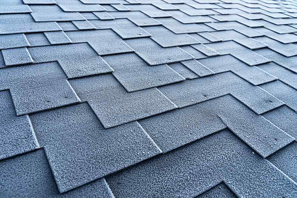 View on asphalt roofing shingles covered with frost.