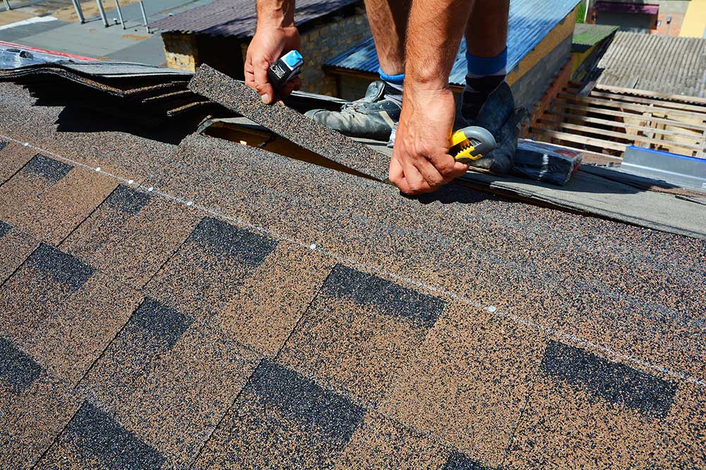 Repairing of roof by cutting felt or bitumen shingles during waterproofing works.