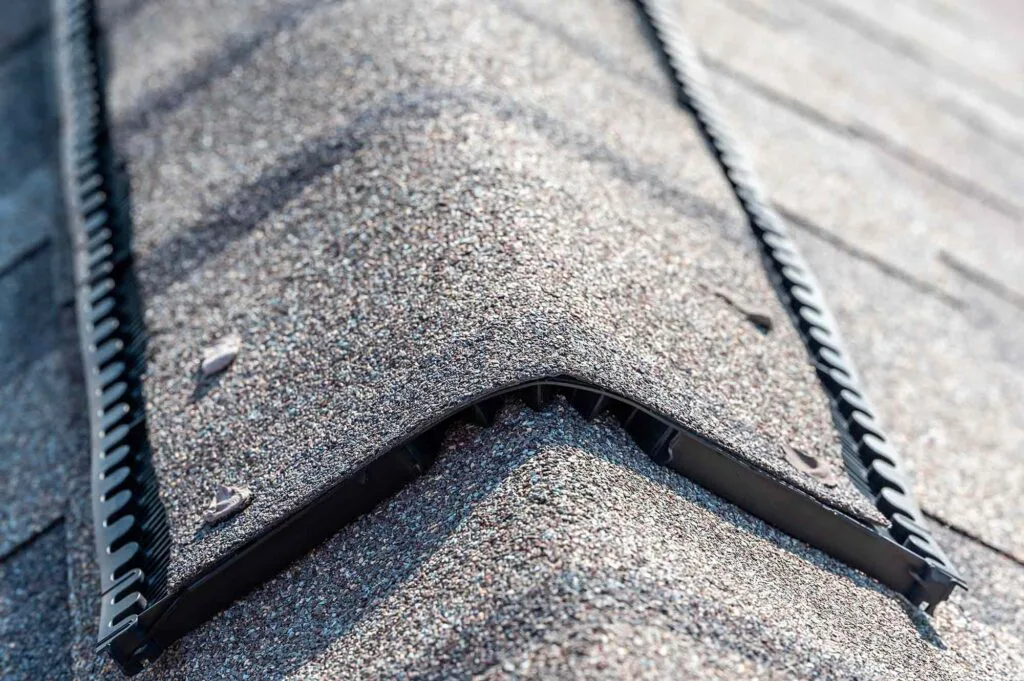 Ridge cap vent installed on a shingle roof for passive attic ventilation on a residential house.