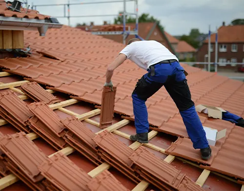 roofing red clay tiles, roofer builder with white t shirt on rooftop of a house and roof construction site